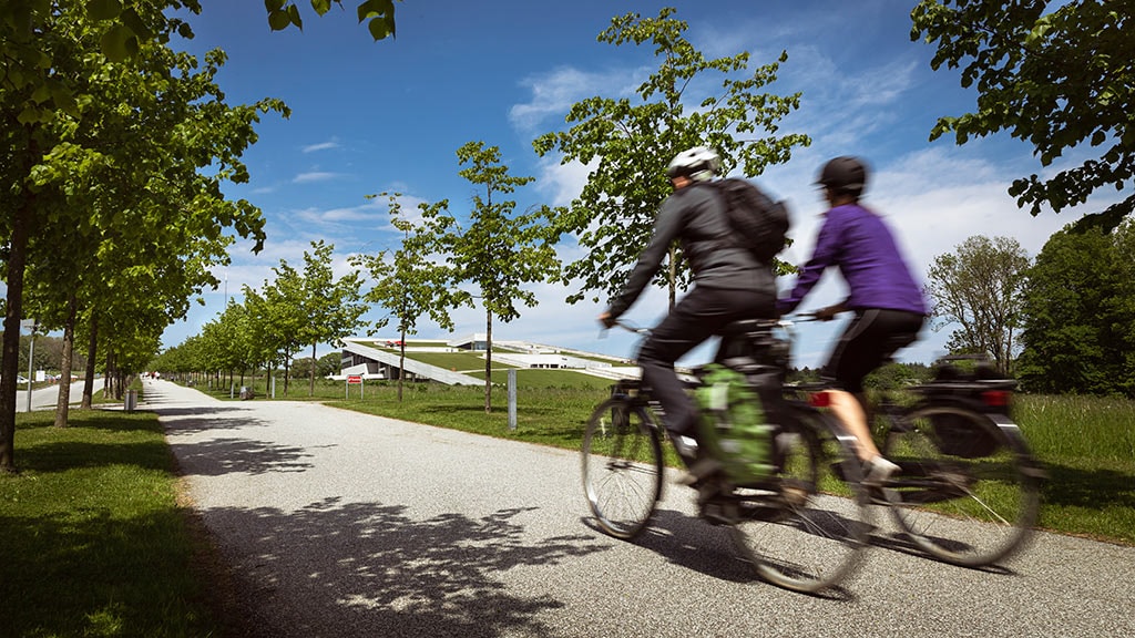 To personer cykler foran Moesgaard Museum