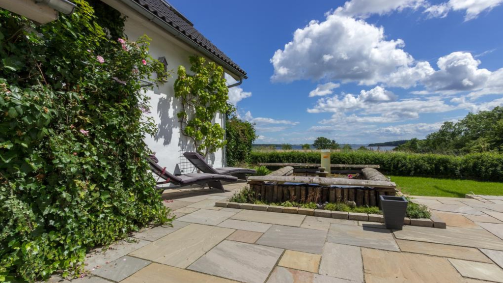 Terrasse mit Steinbelag, eine Sandkiste und ein Blick auf dem grünen Feld