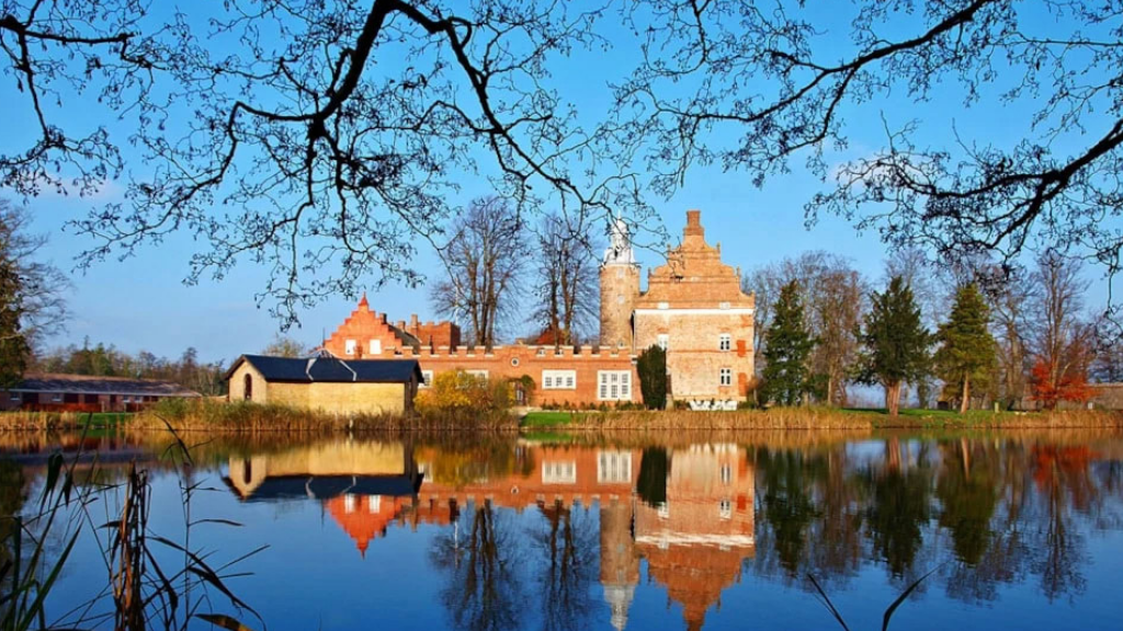 Rødt slot med rødt tag spejler sig flot i vandet.