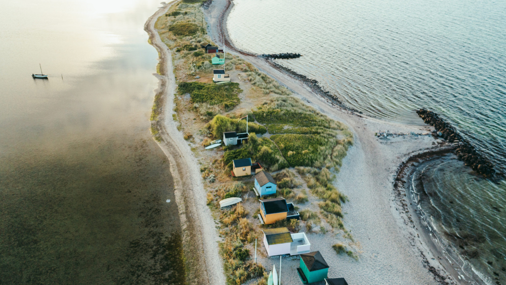 Bunte Sommerhäuser von oben aus der Drohnenperspektive mit Wasser auf beiden Seiten.