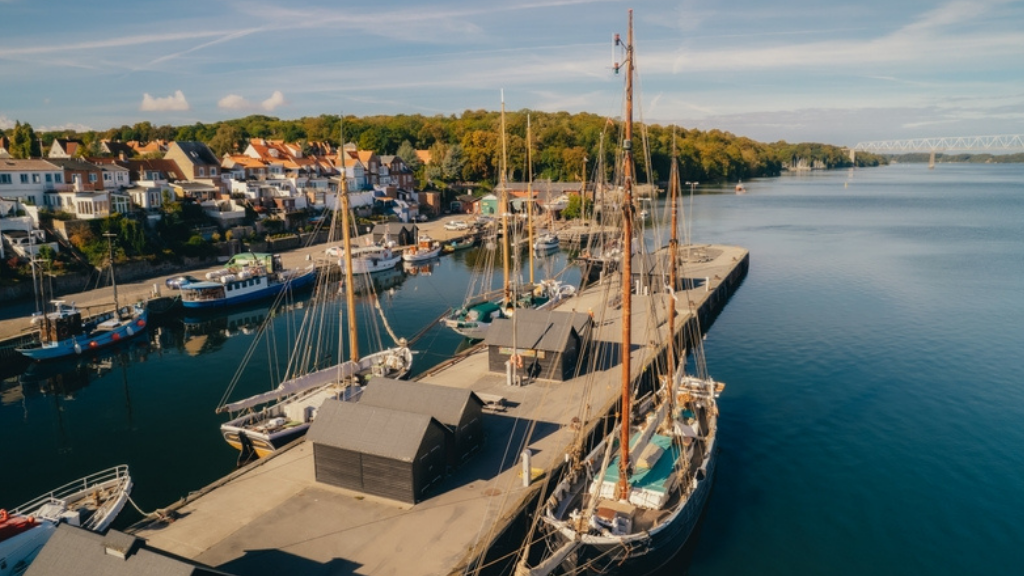 Droneshot af en havneplads med huse og natur i baggrunden.