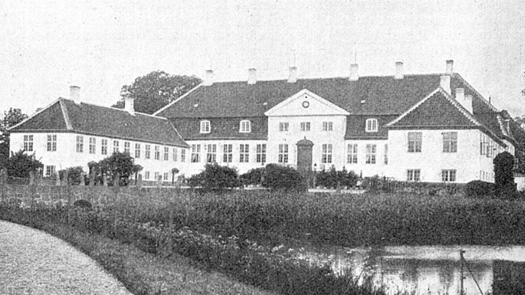 Hvid herregård med mørkt tag set i sort/hvid.